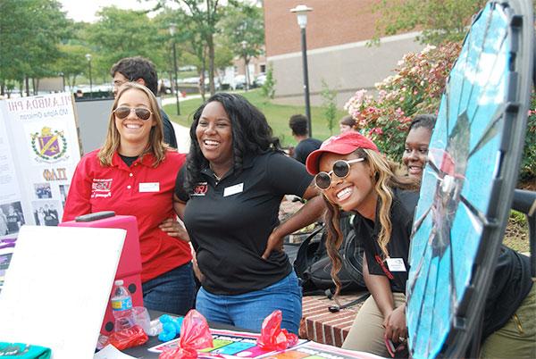 Girls smile at visitors to their booth during a student organization event